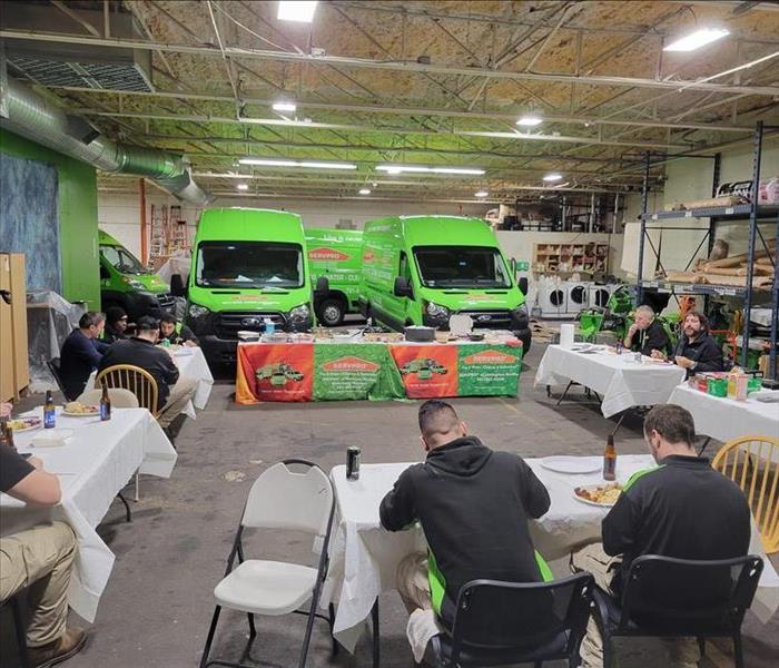 SERVPRO team having dinner in warehouse with vans in back ground