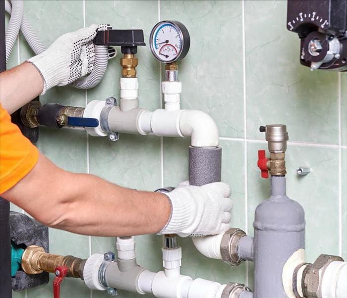 plumber's hands on pipes with valves