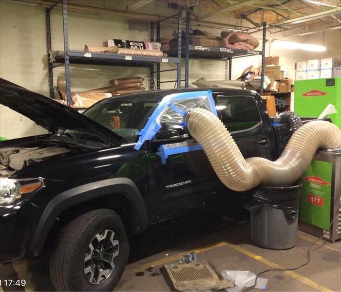 Toyota Tacoma pick-up truck with dehumidifier next to it and air hose running into window