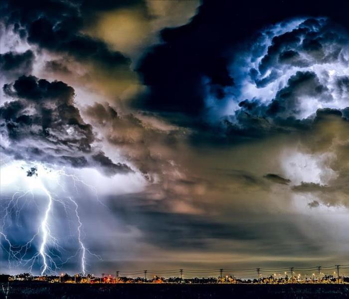 Severe storm clouds with lightning strikes over city at night