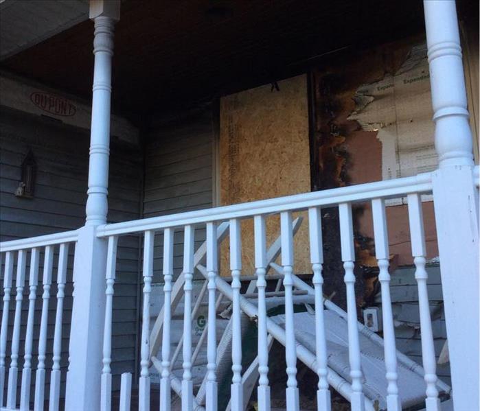 porch with fire and smoke damage and a boarded up window